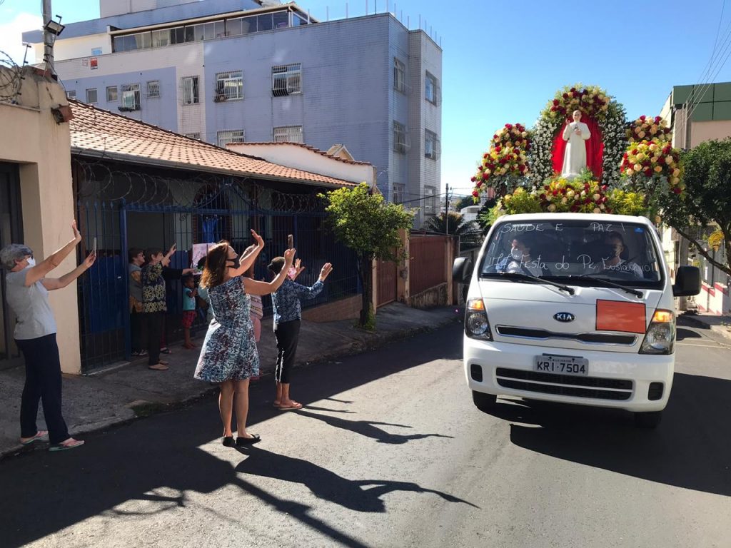 Devotos do beato Padre Eustáquio levantando as mãos e aplaudindo a passagem do carro-andor com a imagem do bem-aventurado.