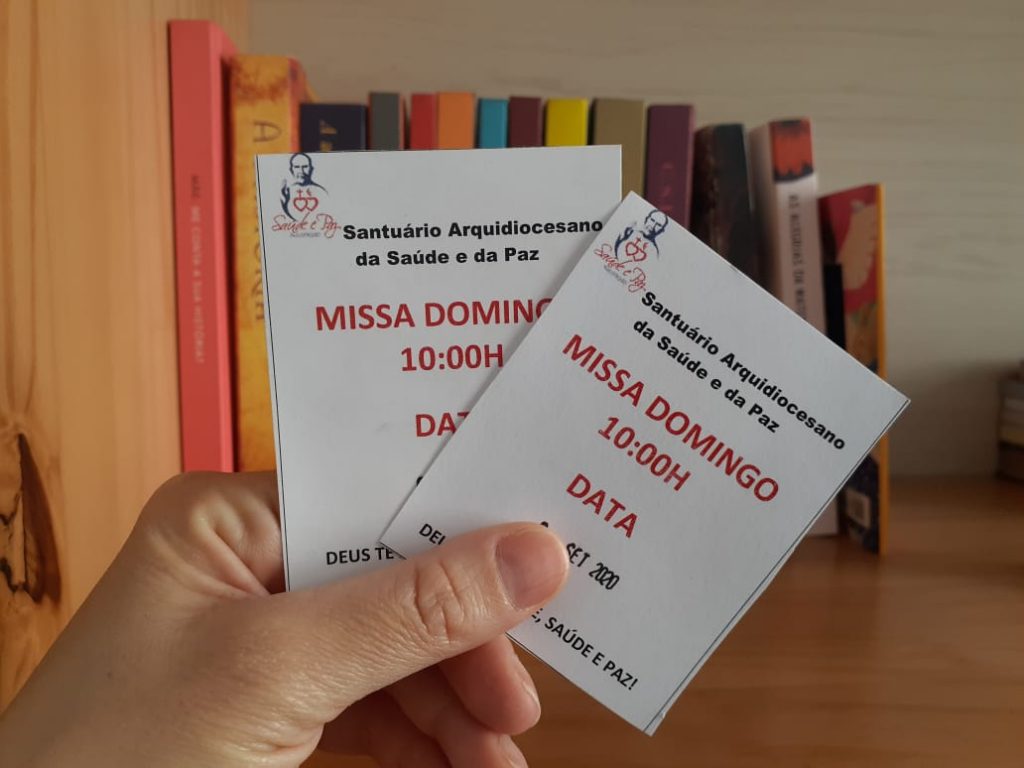 Uma mão segura duas senhas para participação das missas presenciais do Santuário