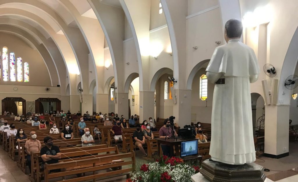 Devotos sentados de frente à imagem do Padre Eustáquio, mantendo o distanciamento social.
