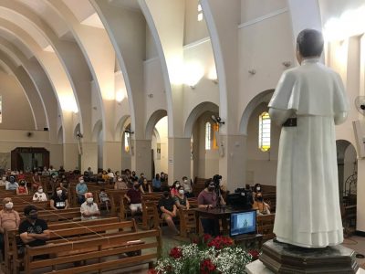 Devotos sentados de frente à imagem do Padre Eustáquio, mantendo o distanciamento social.