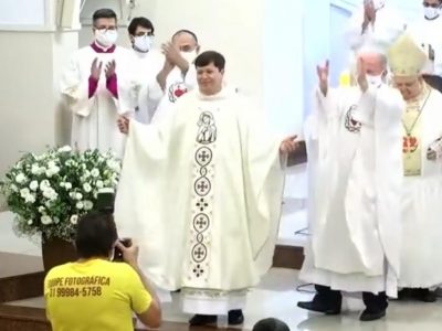 Padre armin, no altar da igreja do Padre Eustáquio, se apresentando para a comunidade como novo padre, durante sua ordenação. Sendo aplaudido e fotografado